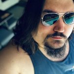 AJ Hanson's Headshot - Him staring at the camera while wearing sunglasses